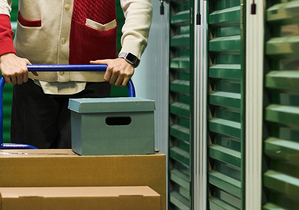 two men moving cardboard boxes in an office space with seven packages stacked on the floor