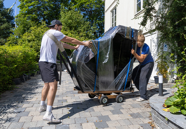 men packing furniture with plastic wrap in a room filled with moving boxes preparing for a relocation process involving 8 items